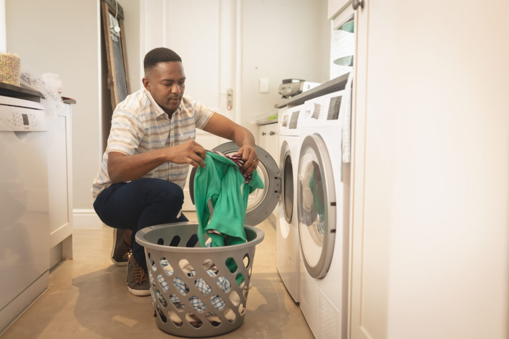 African American man pulling clothes out of a dryer