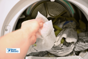 a hand putting dryer sheets in the dryer