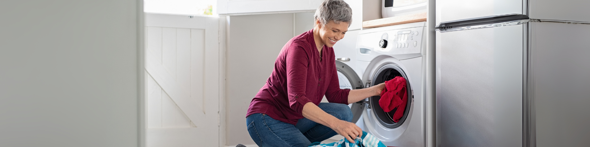 woman smiles as she puts clothes in a dryer